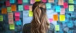 © -Quantum Pixels- - Woman mentoring in an office with colorful sticky notes on the wall, promoting skill development and collaboration during a training session.