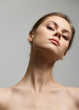© SHOTPRIME STUDIO - Elegant young woman with minimal makeup, posing confidently against a soft gray background. Beauty and self-expression concept.
