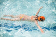 © Cavan Images - 5 year old girl floating on stomach in pool with swim cap