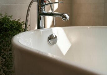 Sunlight reflecting on a white bathtub and chrome faucet in a modern bathroom, creating a relaxing atmosphere