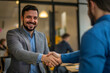 © Kanishka - Two Men in Business Casual Attire Shaking Hands in an Office Setting