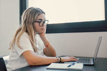 Wall Mural - Happy young blonde business woman entrepreneur using computer looking at screen working in internet sit at office desk, smiling millennial female professional employee typing email on laptop workplace