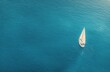 © olegganko - Sailing on calm blue waters with a lone boat under a sunny sky