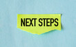 © Pawel - Next Steps text on yellow stickers attached on blue background.