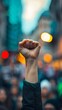 © COK House - A close-up image shows a raised white fist in a dark background with blurred lights, suggesting a night scene, conveying intensity and solidarity, possibly linked to protests