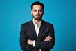© Metehan - A man in a suit stands with his arms crossed against a blue background