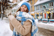 © maxbelchenko - Happy woman in winter clothes walks on the street. Light all around. Winter holidays.