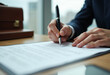 © Imagehub - A person in a suit carefully signs an important legal document using a pen.