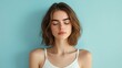 © Lion - Young white woman with shoulder length brown hair wearing a white tank top, eyes closed, feeling relaxed, soft blue background, studio lighting