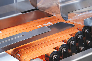 Poster - A conveyor belt with orange strips on it. The belt is moving and the orange strips are being cut
