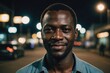 © ThomasLENNE - Close portrait of a smiling 40s Guinean man looking at the camera, Guinean city outdoors at night blurred background