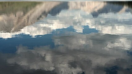 Wall Mural - reflection of a mountain, blue sky and clouds in a calm lake with small ripples