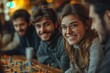 © Roman - Smiling young couple sitting at a table with board game pieces