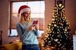 © Drazen - Cheerful woman receiving text message on Christmas at home.