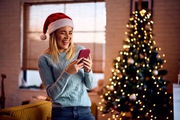 cheerful woman receiving text message on christmas at home.