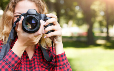 Wall Mural - Young female student taking photos in the park with camera. Photography classes, education and remote working concept, copy space, closeup