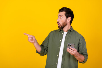 Poster - Portrait of nice young man indicate finger empty space wear khaki shirt isolated on yellow color background