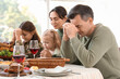 © Pixel-Shot - Happy family praying before dinner at festive table on Thanksgiving Day