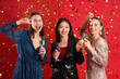 © Pixel-Shot - Beautiful young women with champagne and confetti on red background. New Year celebration