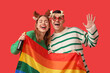 © Pixel-Shot - Young couple with LGBT flag and champagne on red background