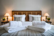 © Nida - Hotel bed with white linens, folded towels create serene, welcoming ambiance