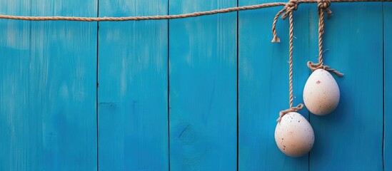 Poster - Easter eggs suspended on a rope in front of a vibrant blue wooden background creating a festive and colorful spring atmosphere