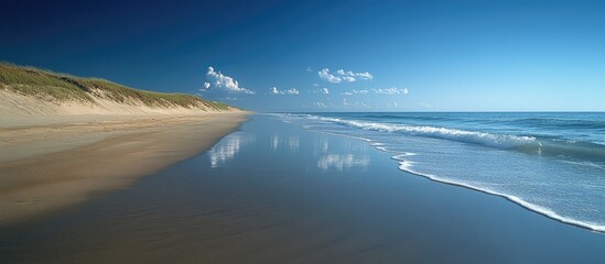 Poster - Serene beach landscape with clear blue sky and pristine sandy shoreline reflecting on calm ocean waters
