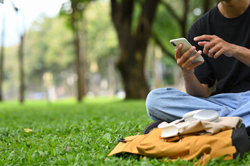 Man using mobile phone on the grass taking a break during relaxing outdoor activity