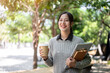 © bongkarn - A charming, happy Asian female college student walks along the footpath on campus on a bright day.