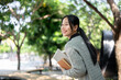 © bongkarn - A charming, happy Asian female college student walks along the footpath on campus on a bright day.