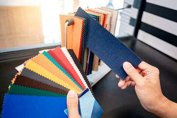 fabric swatch material choice. designer hand compares fabric sample pieces from color collection at 