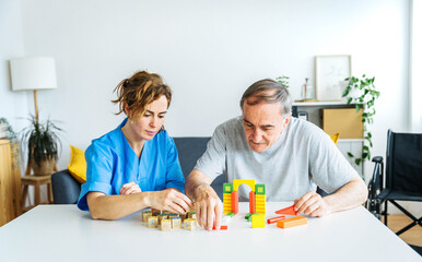 professional nurse caregiver in geriatric clinic helps senior man with alzheimer's disease - old pat