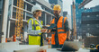© Gorodenkoff - Technical Inspector Interviewing a Construction Manager on Behalf of an Occupational Health and Safety Commission. Female Specialist Using a Tablet Computer to Question a Construction Worker