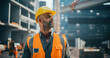 © Gorodenkoff - Portrait of Happy Construction Worker Carrying a Theodolite, Posing for Camera. Professional Heavy Industry Engineer Wearing Safety Orange Uniform and Protective Hard Hat