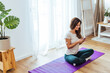 © Dragana Gordic - Relaxed Woman Using Smartphone While Sitting on Yoga Mat at Home
