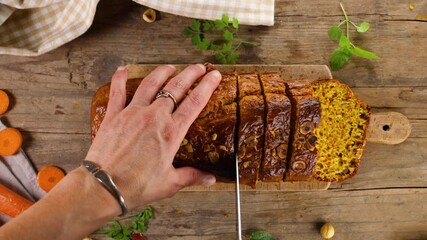 Wall Mural - woman's hand cutting loaf cake on wooden board