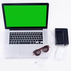 Poster - Laptop, green screen and top view on desk for space, mockup and phone on white studio background. Chroma key, computer monitor and advertising on table, marketing headphones and sunglasses promo