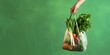 © RM Graphics - Hand holding bag with fresh vegetables over green background