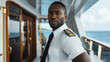 © Duka Mer - A captain, standing on the bridge, poses for a photo while sailing in the ocean on a cruise, looking at the camera.