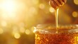 © gudangPIXEL - Golden honey pouring from a wooden dipper into a glass jar against a bokeh background.