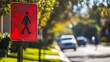 © Phatharaporn - A bright red pedestrian crossing sign stands amidst a tranquil street scene, indicating safety for walkers in a suburban setting.