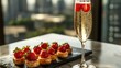 © Albert - a glass of champagne and a plate of strawberries on a table The plate is black and the glass is filled with a bubbly liquid, likely champagne, and the strawberries