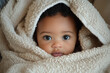 © kazakova0684 - An Afro-American baby wrapped in a cozy white blanket, gazing curiously at the camera