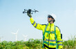 © narong - Wind turbine or windmill workers or technician hold drone to check before work in workplace field during day time and wind turbine are in the background.