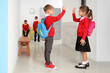 © Pixel-Shot - Little pupils with backpacks giving each other high-five at school hall