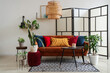 © Pixel-Shot - Interior of stylish living room with brown sofa, colorful cushions and houseplants