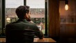 © Jota - A person sits in an empty cafe, looking outside where the rain is gently falling on the windows. The person's expression reflects melancholy and tiredness, while the dim lights of the place create an