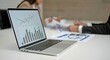 © TAMER YILMAZ - Closeup of laptop with graphs on screen on white modern office desk, preparation for formal meeting of the board of directors, effective management. Office interior. Business success concept.