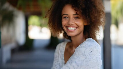 Wall Mural - Young, happy woman with curly hair smiles cheerfully outdoors, reflecting beauty and joy.