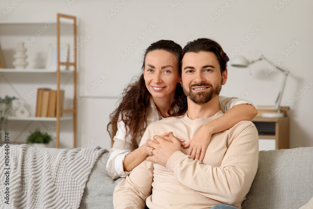 Happy wife hugging her husband on sofa at home